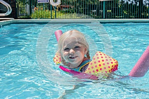 Little blonde girl playing at the pool on a summer day