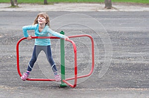 Little blonde girl playing on small merry go round photo