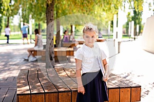 Little blonde girl in school uniform studying at the park