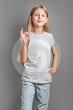 A little blonde girl shows the ok sign