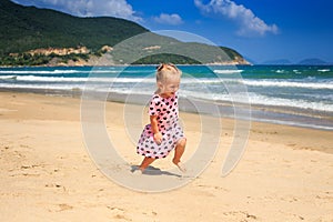 Little Blonde Girl in Spotty Dress Jumps on Sea Beach