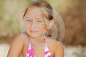 Little blonde girl in swimsuit on the beach