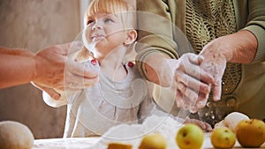 A little blonde girl touching the dough. Shaking off flour from the hands