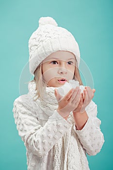 Little blonde girl in a white hat and scarf