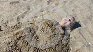 Little blonde haired girl getting buried in sand