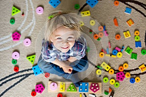 Little blonde toddler child,  boy playing with wooden toys developing and learning