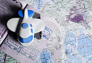 Little blue toy plane lying on the passport page with visa stamps in the word map, toned