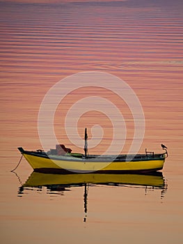 Little boat floating on the calm water under amazing sunset in Quellon, Chiloe Island in Chile