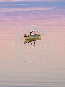 Little boat floating on the calm water under amazing sunset in Quellon, Chiloe Island in Chile