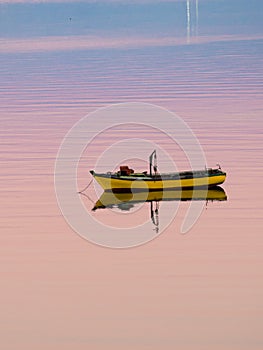 Little boat floating on the calm water under amazing sunset in Quellon, Chiloe Island in Chile