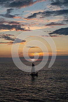 Little boat sails at the warm sunset on the North Sea