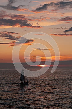 Little boat sails at the warm sunset on the North Sea