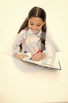 Little bookworm. Writing notices. Girl child writes hometask while sit table white background. Schoolgirl studying photo