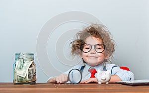 Little boss portrait in suit and glasses with money. Businessman in office. Kid holding money. Young business boy or