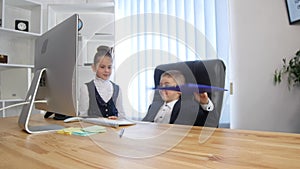 Little boss and secretary. Cheerful little boy in suit gives orders while little girl in formalwear standing near him