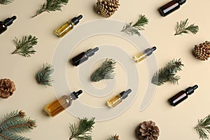 Little bottles with essential oils among pine branches and cones on color background