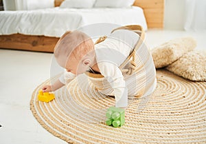 Little boy 1 year old, playing near the crib, early development