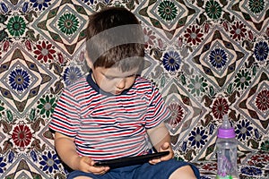 A little boy 2-3 years old looks into the screen of the tablet. Cartoons for children, screen time, children`s dependence on the