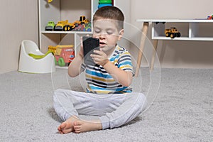 A little boy 3-4 years old looks into the screen of the tablet. Cartoons for children, screen time, children& x27;s