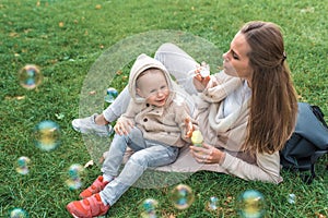 Little boy 3-5 years old son, catches air and soap bubbles. Mom woman plays and inflates bubbles, happy play having fun
