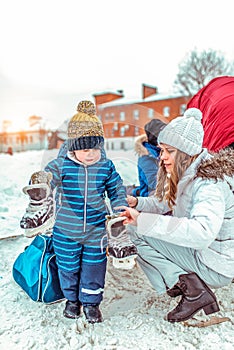 A little boy is 3-6 years old, in the winter in the city on a public skating rink. In a blue jumpsuit and a warm hat