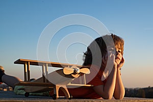 Little boy 7 year old with wooden plane, boy wants to become pilot and astronaut. Happy child play with toy airplane