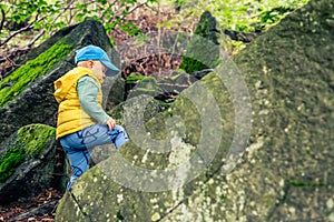 Little boy adventure hiking and climbing in mountains