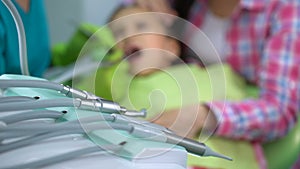 Little boy afraid of dental drill treatment, mother soothing child, background