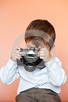 Little boy with aged retro camera. Child with an old camera