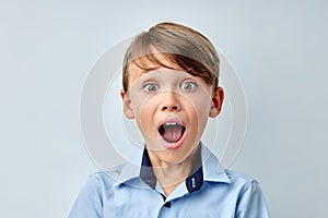 little boy amazed by news with opened mouth isolated gray color background