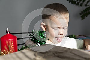 A little boy in anticipation of Christmas and new year, shows his tongue