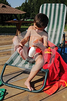 Little boy applying sunscreen lotion