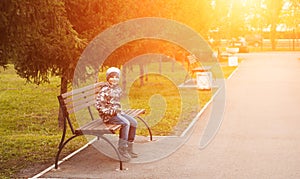 Little boy in autumn Park sitting on a bench,