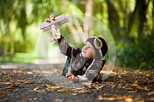 Little boy with aviator hat, lying on the ground in a park