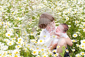 Little boy with baby sister in a daisy flower field