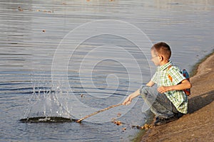 Little boy with backpack near pond