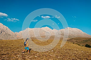 a little boy with a backpack walks along a path against the backdrop of mountains. travel with children to the mountains. Turkey.