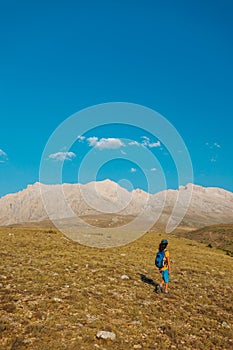 a little boy with a backpack walks along a path against the backdrop of mountains. travel with children to the mountains. Turkey.