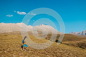 a little boy with a backpack walks along a path against the backdrop of mountains. travel with children to the mountains. Turkey.