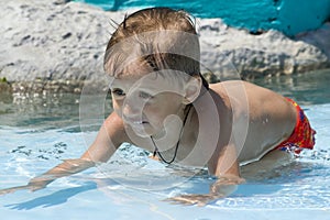 Little boy bathes on shoal in a pool photo