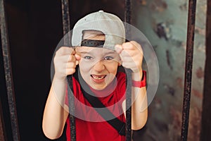 Little boy behind iron bars. Kid on an excursion in an old castle