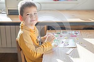 Little boy being creative making homemade do it yourself  dinosaur mosaic. Supporting creativity, learning by doing, learning