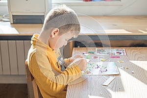 Little boy being creative making homemade do it yourself  dinosaur mosaic. Supporting creativity, learning by doing, learning