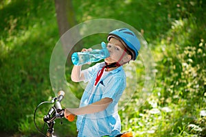 Little boy with bicycle drinks water