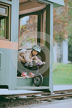 A little boy on a bicycle sticks his head out of the train carriage