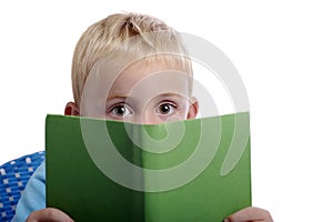 Little boy with big eyes looking from over a book