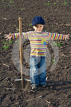 Little boy with big shovel in the field