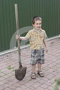 Little boy with a big shovel. little happy boy working with shovel in garden. boy 5 years old keeping a big shovel