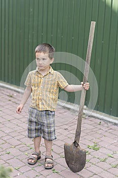 Little boy with a big shovel. little happy boy working with shovel in garden. boy 5 years old keeping a big shovel