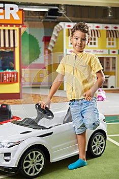 Little boy with a big toy car looking at camera.